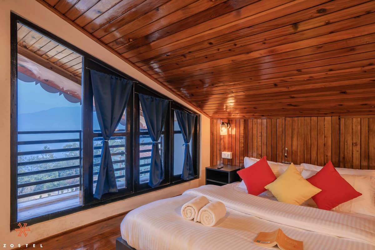 A wooden-paneled room with a bed, pillows, and a window with curtains.