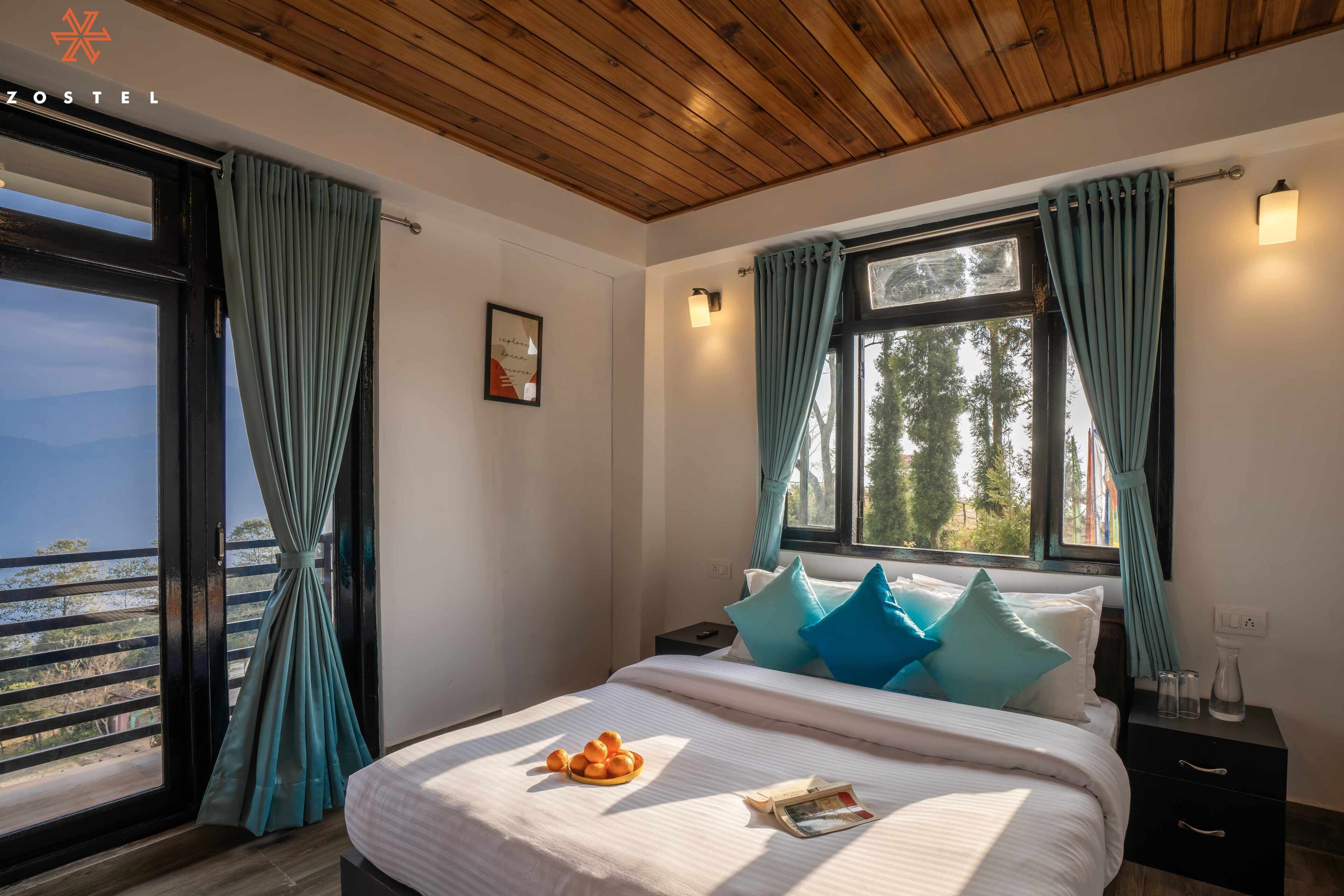 Une chambre à coucher avec un lit, une table de chevet, une fenêtre avec des rideaux et une vue sur l’extérieur.