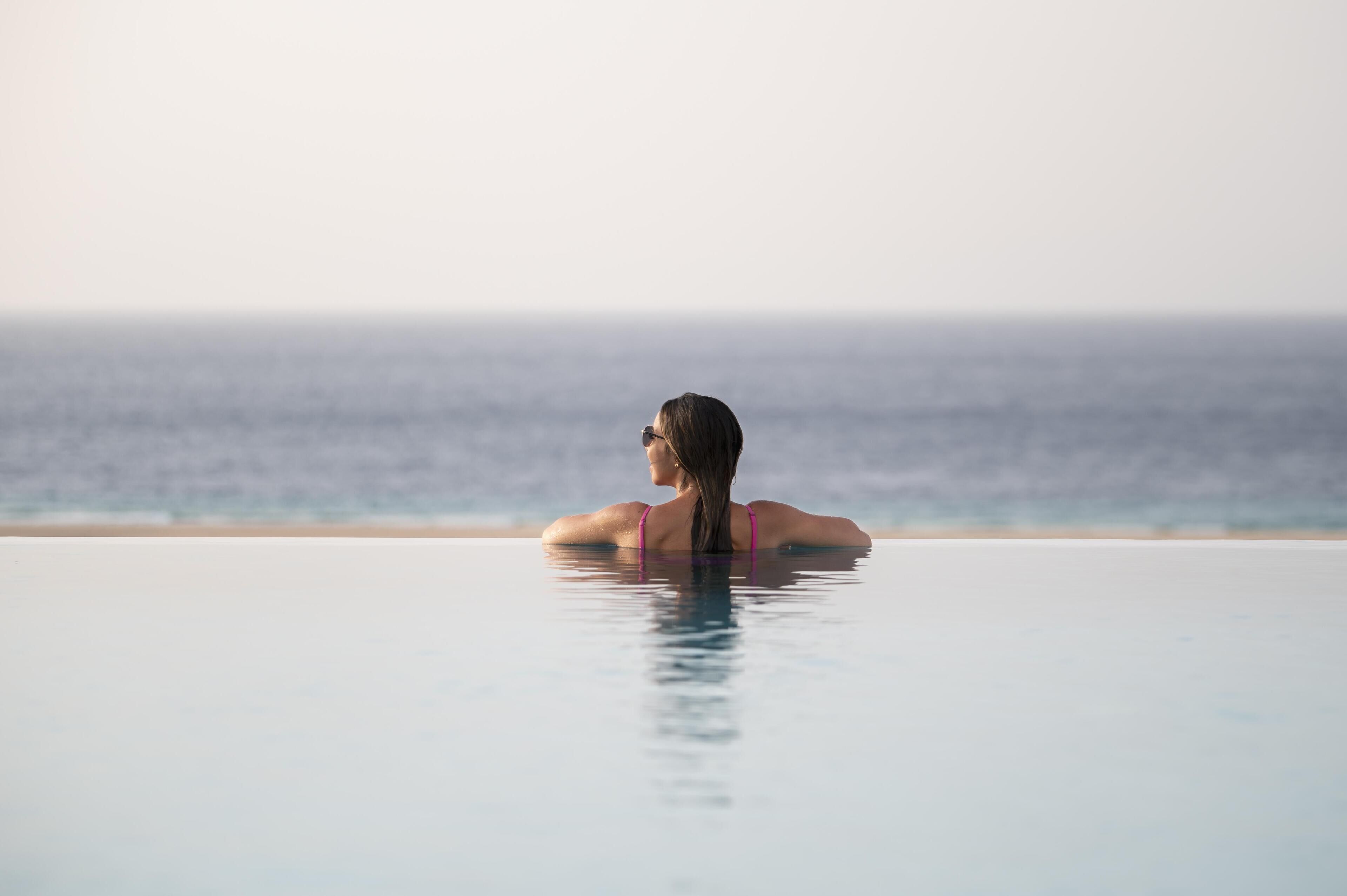 A person in a swimming pool with a view of the ocean.