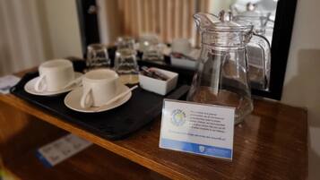 Una bandeja con una jarrón de vidrio, dos tazas y un cartel que promociona botellas de agua sin plástico.