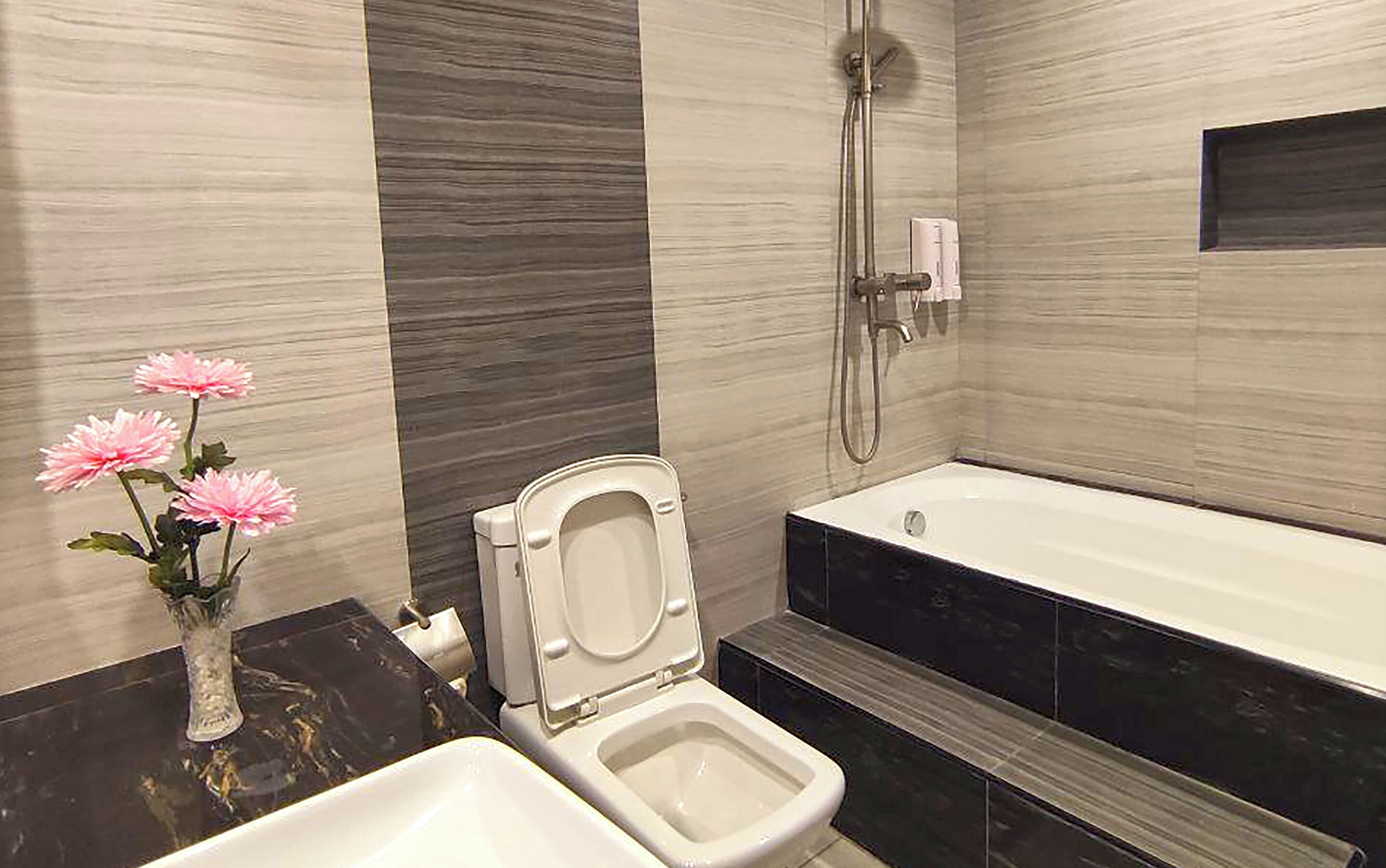 A modern bathroom with a toilet, bidet, and bathtub.
