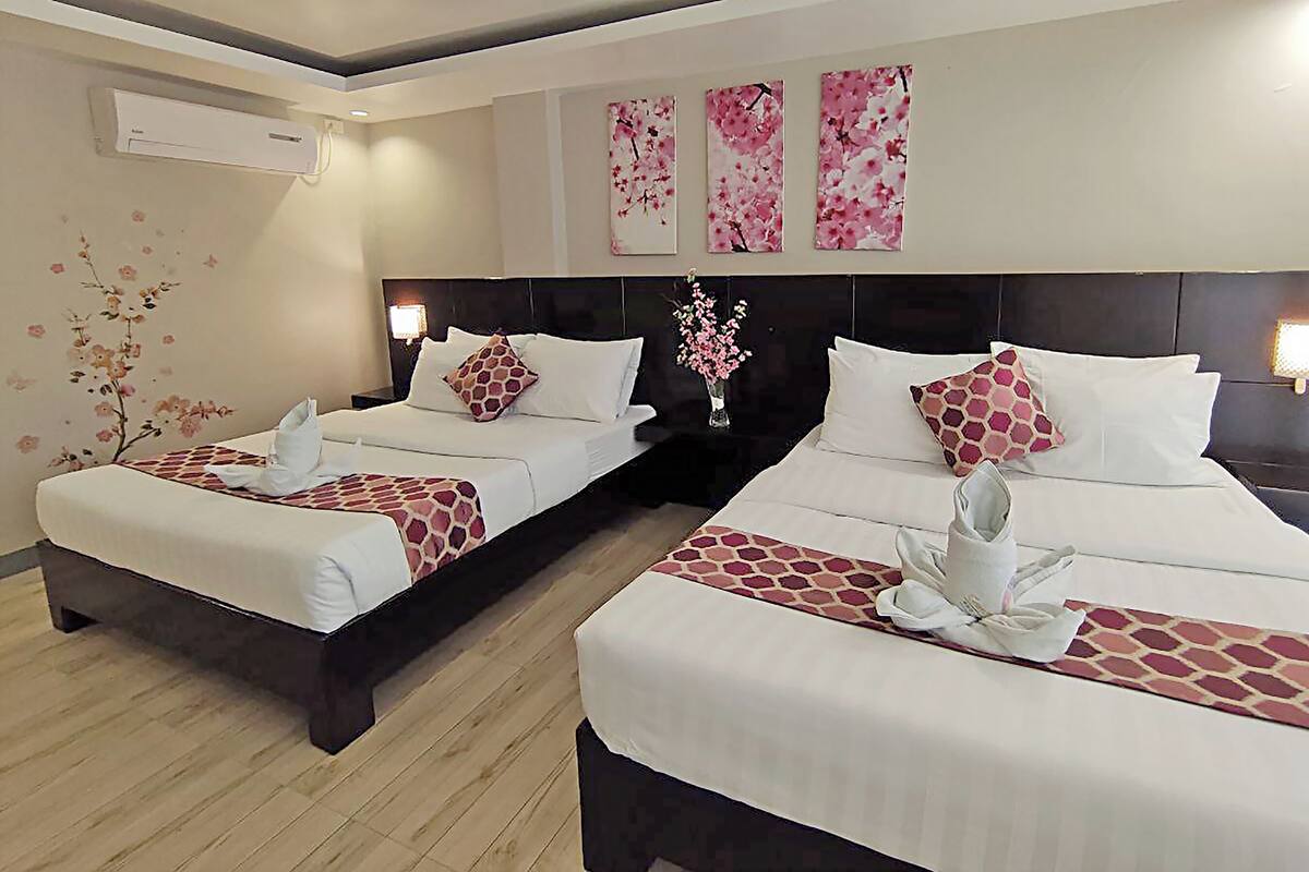 A hotel room with two beds, a nightstand with a lamp, and wall art.