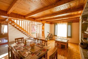 A wooden interior with a dining area, a staircase, and a bicycle. - Zostel Homes Cheog - Shimla (Theog)