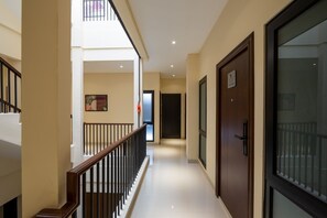 A hotel corridor with a wooden railing, a glass door, and a framed picture on the wall. - Cove Tripuri House Bali (Tuban)
