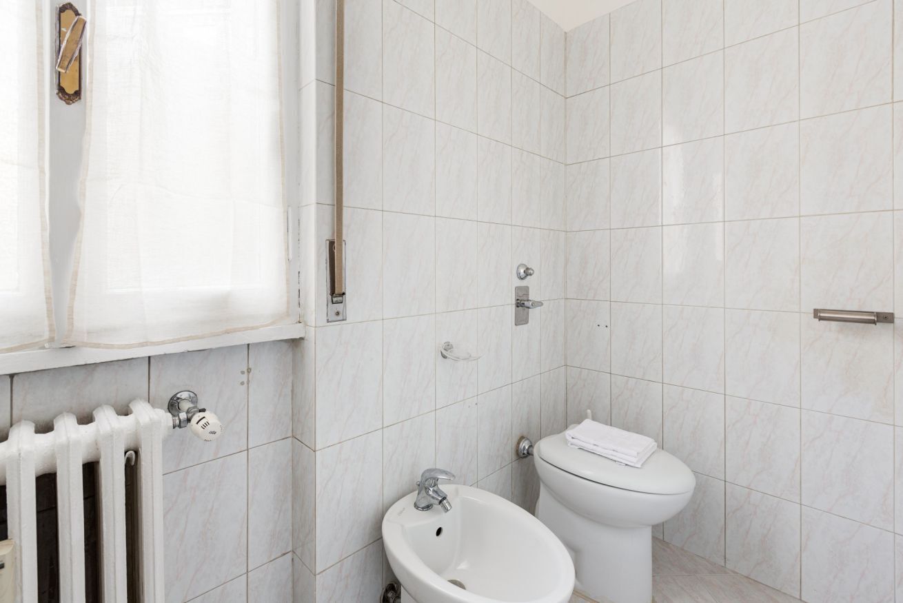 A bathroom with a toilet, bidet, and a radiator.
