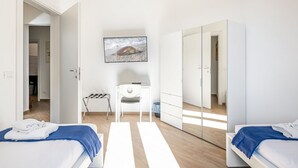 Et moderne soveværelse med to senge, et skrivebord, en stol, et fjernsyn og en garderobe.
