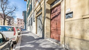 En smal gade med parkerede biler, en rød dør og en postkasse på en bygning.