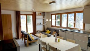 Een moderne, open woonruimte met een eethoek, bank en keuken.