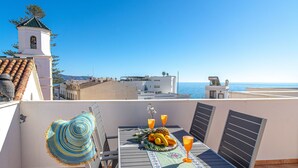 Terraza en la azotea con una mesa para dos, con vistas a la costa.