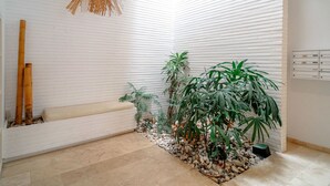 Un interior moderno con paredes de ladrillo blanco, un banco de madera y diversas plantas.