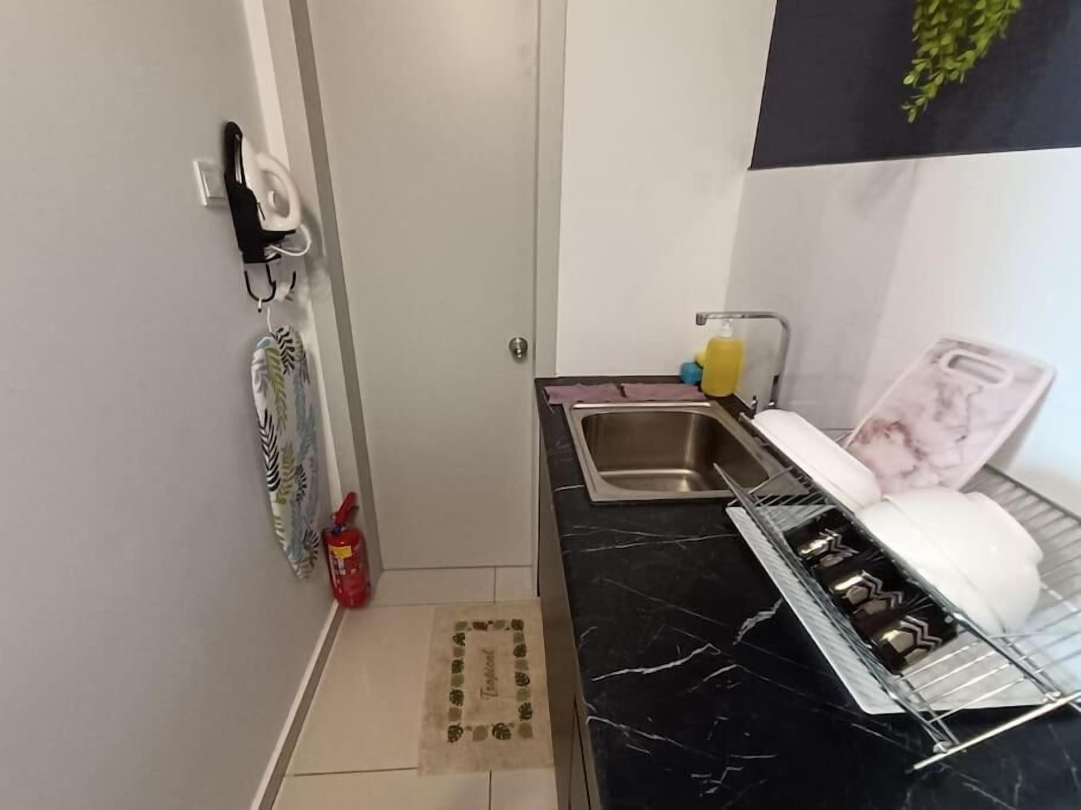 Una cocina compacta con encimera de mármol negro, un lavamanos de acero inoxidable y un escurreplatos.