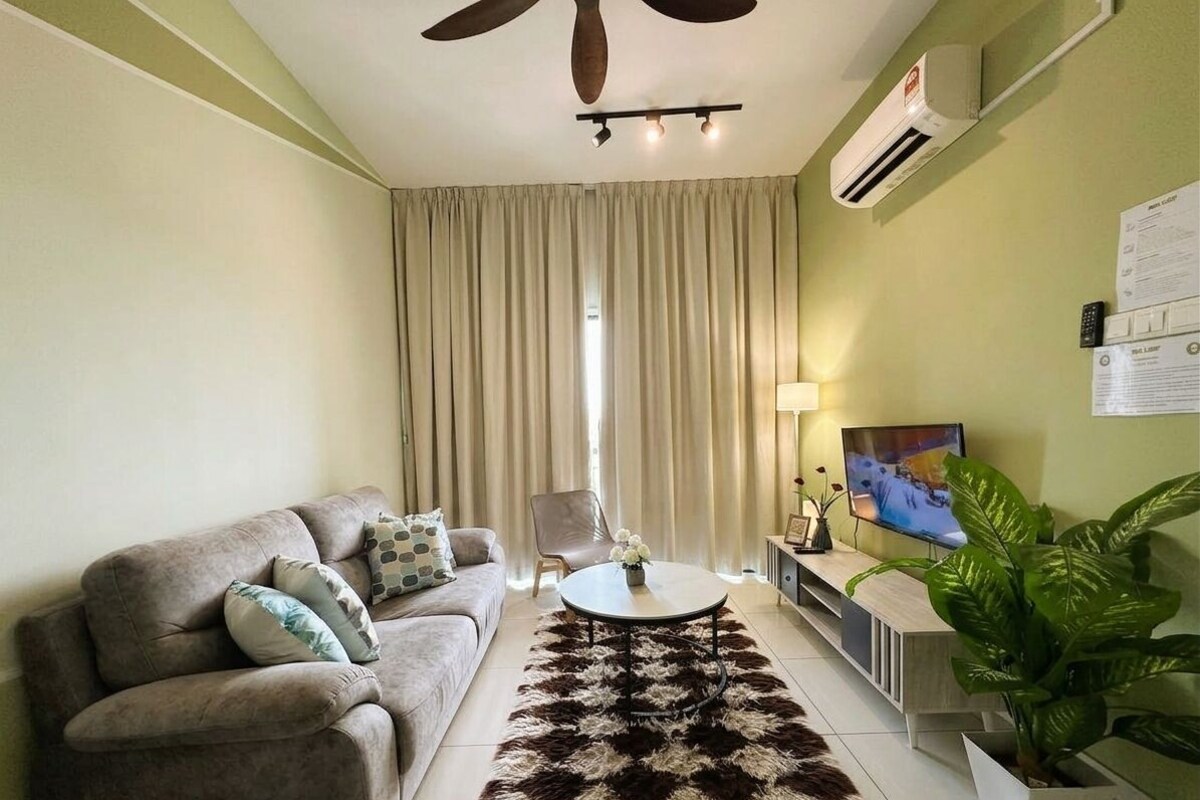 A living room with a sofa, a coffee table, a TV, and a plant.