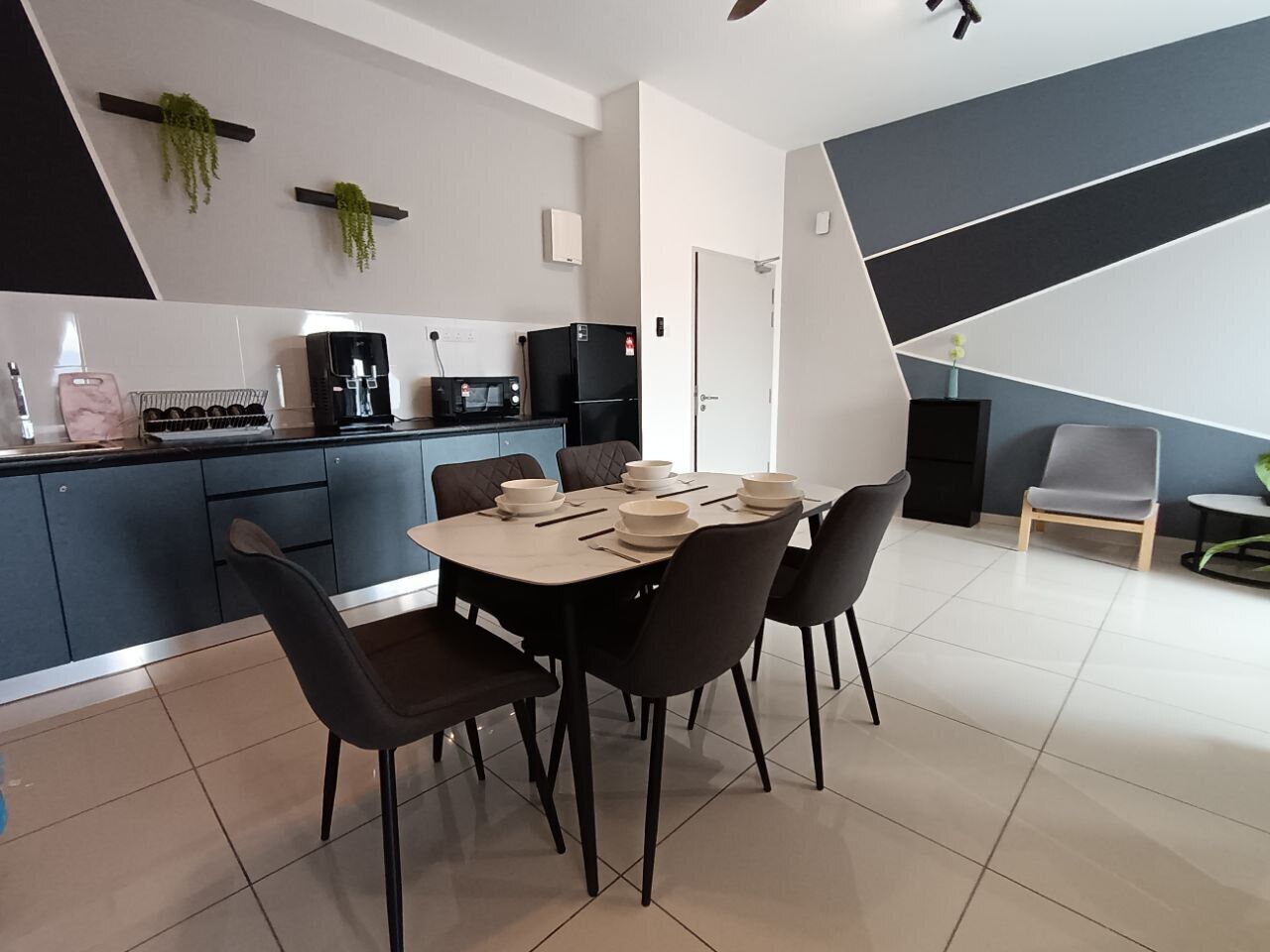 A modern kitchen with dark cabinets, a dining table set with plates, and a microwave.