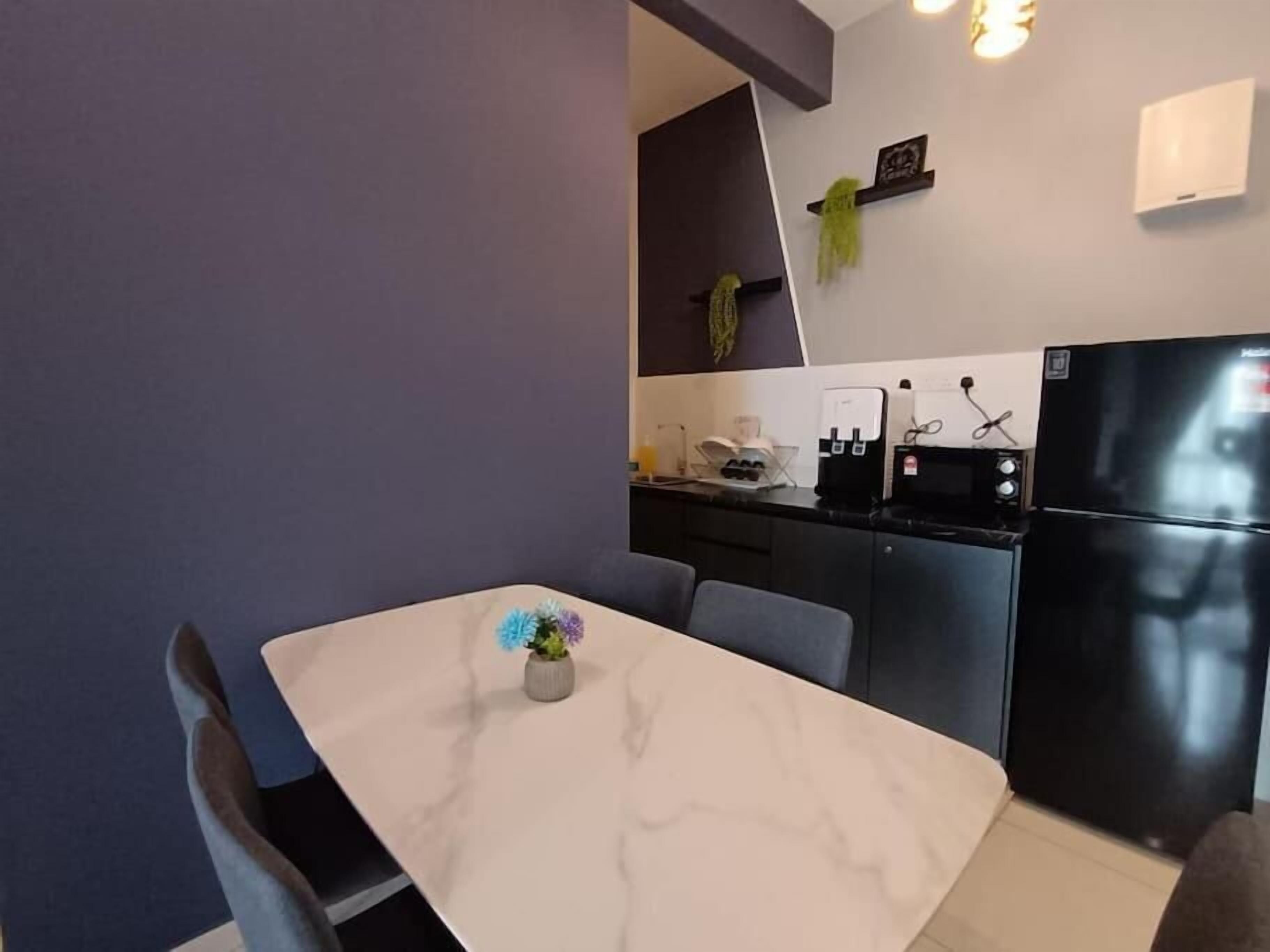 Una cocina moderna con encimera de mármol, un refrigerador negro y una pequeña planta en maceta en la pared.