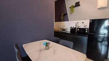 Una cocina moderna con encimera de mármol, un refrigerador negro y una pequeña planta en maceta en la pared.
