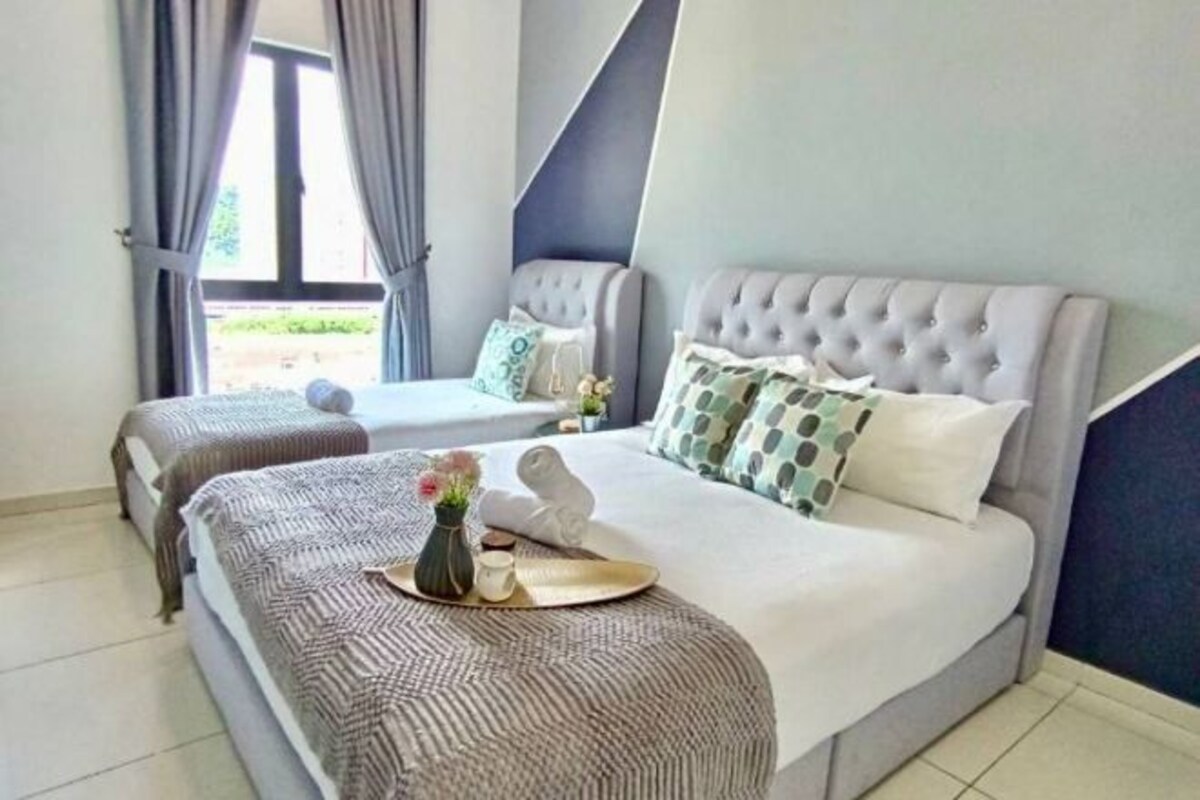 Habitación de hotel con dos camas, un ventanal grande y vistas al exterior.