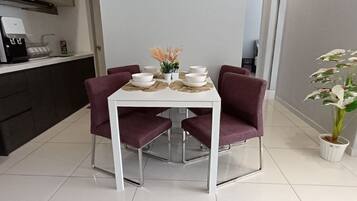 A dining area with a white table, four purple chairs, and a potted plant.