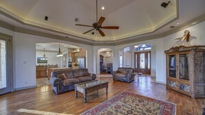 A spacious living room with hardwood floors, leather sofas, a coffee table, and a large rug. - Texas River Ranch-518 Acres; 2 Homes, Sleeps 21; +/- 3 Miles of River Frontage (Brown Wood)