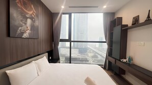 A hotel room with a large bed, a painting of a rose, a television, and a view of city buildings. - HKG-Vinhomes Sky Lake - Luxury Apartment (Hanoi)