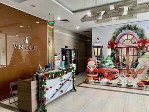A hotel reception area with a Christmas display including a decorated car, Santa Claus, and a Christmas tree. - HKG-Vinhomes Sky Lake - Luxury Apartment (Hanoi)