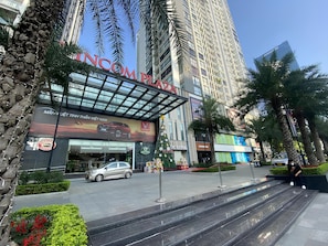 A modern hotel with a prominent entrance, a car parked in front, and a staircase leading to the entrance. - HKG-Vinhomes Sky Lake - Luxury Apartment (Hanoi)