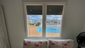 A room with a view of a swimming pool through a window.