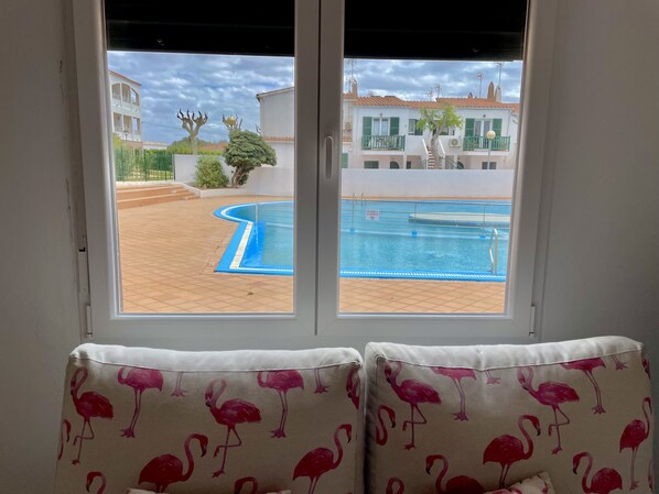 A view of a swimming pool and buildings through a window.