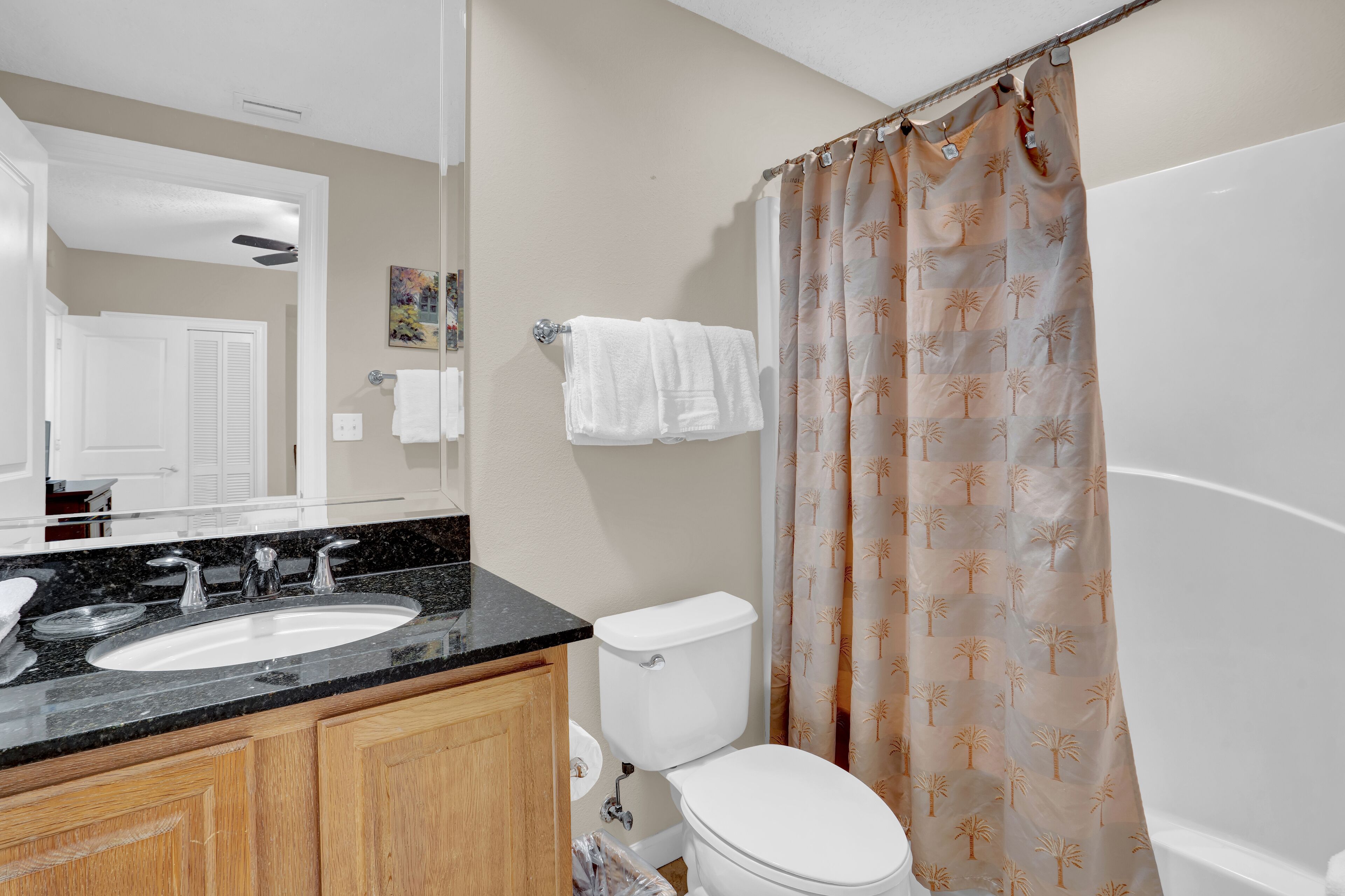 Bagno con doppio lavandino, servizi igienici e tenda da doccia con motivi tropicali.