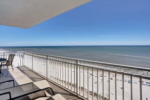 A balcony with a view of the beach and ocean.