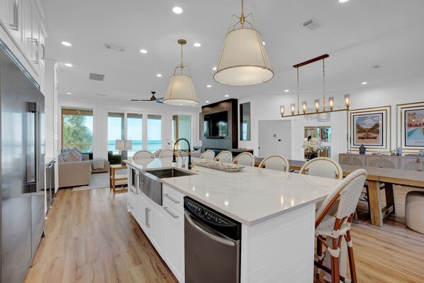 A modern kitchen with a central island, white cabinetry, and pendant lighting.