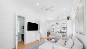 A modern living room with a white sofa, a coffee table, and a TV mounted on the wall.