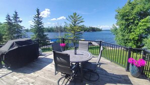 A wooden deck with a round table and chairs, overlooking a lake with trees and a clear sky. - Rainy Dream Vacation - Spacious accomodations, large yard, incredible view!

 (International Falls)