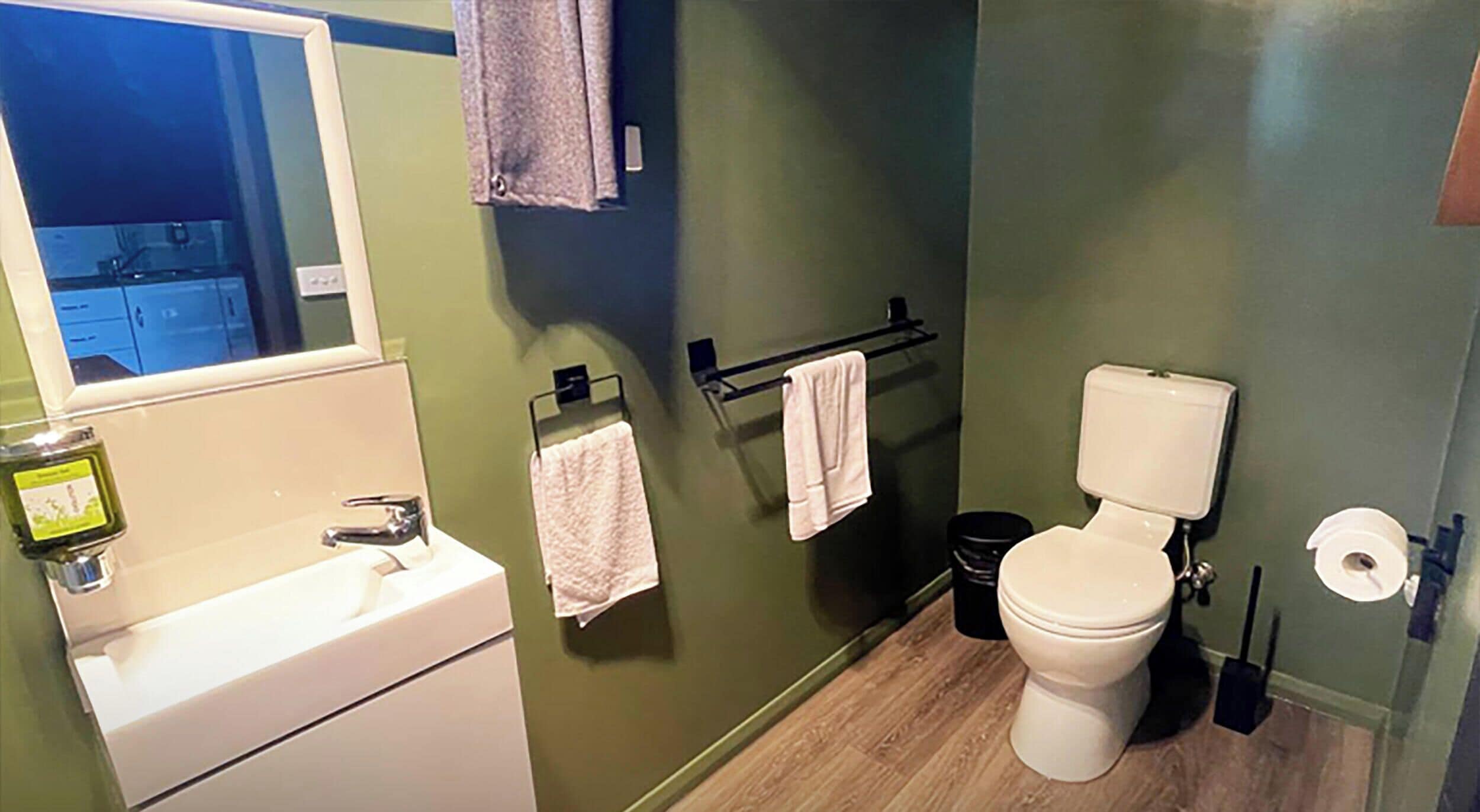 Ein Badezimmer mit Waschbecken, Spiegel, Toilette und Handtuchhalter.
