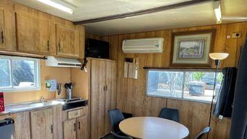 Una cocina compacta con armarios de madera, un microondas, un lavamanos y una zona de comedor con una mesa y sillas.