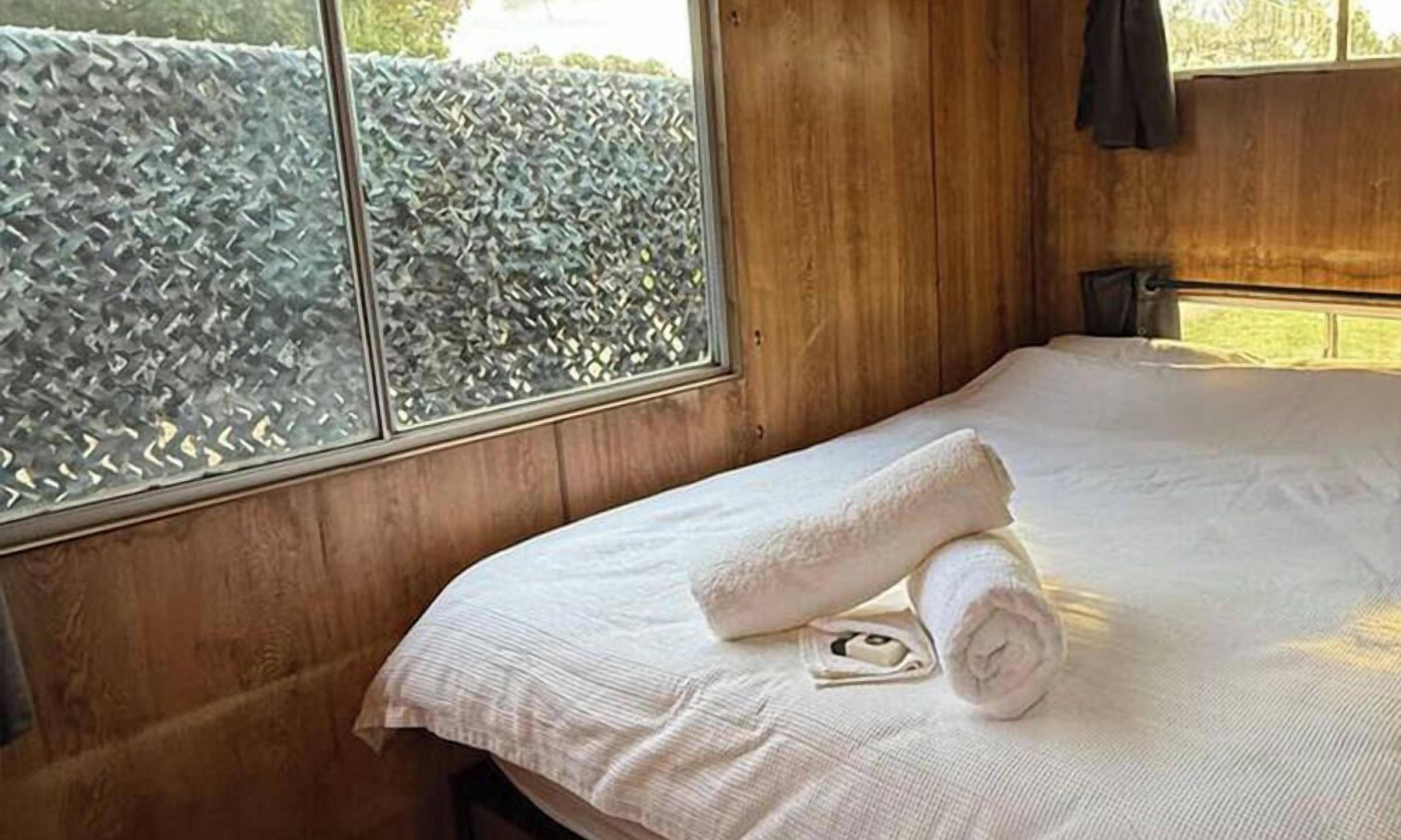 A wooden room with a bed, a window, and a wall.