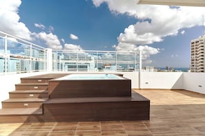 A rooftop terrace with a hot tub, wooden steps, and a glass railing overlooking a cityscape. - Oasis Urbano Family 2br Pool Gym Lm22-8b (Santo Domingo)