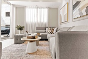 Ein modernes Wohnzimmer mit grauem Sofa, rundem Couchtisch und einem Blumentopf.