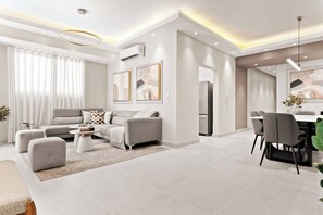 A modern living room with a sofa, coffee table, and dining area. - Oasis Urbano Family 2br Pool Gym Lm22-8b (Santo Domingo)