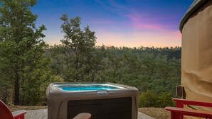 A hot tub on a wooden deck with a view of a forested area. - Scenic forest yurt w/ hot tub & river access (Wardensville)