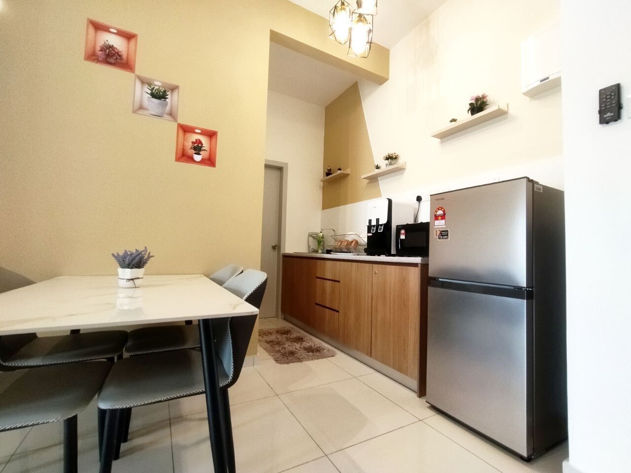 Una cocina funcional con refrigerador, una mesa de comedor con sillas y una pequeña encimera con lavamanos.