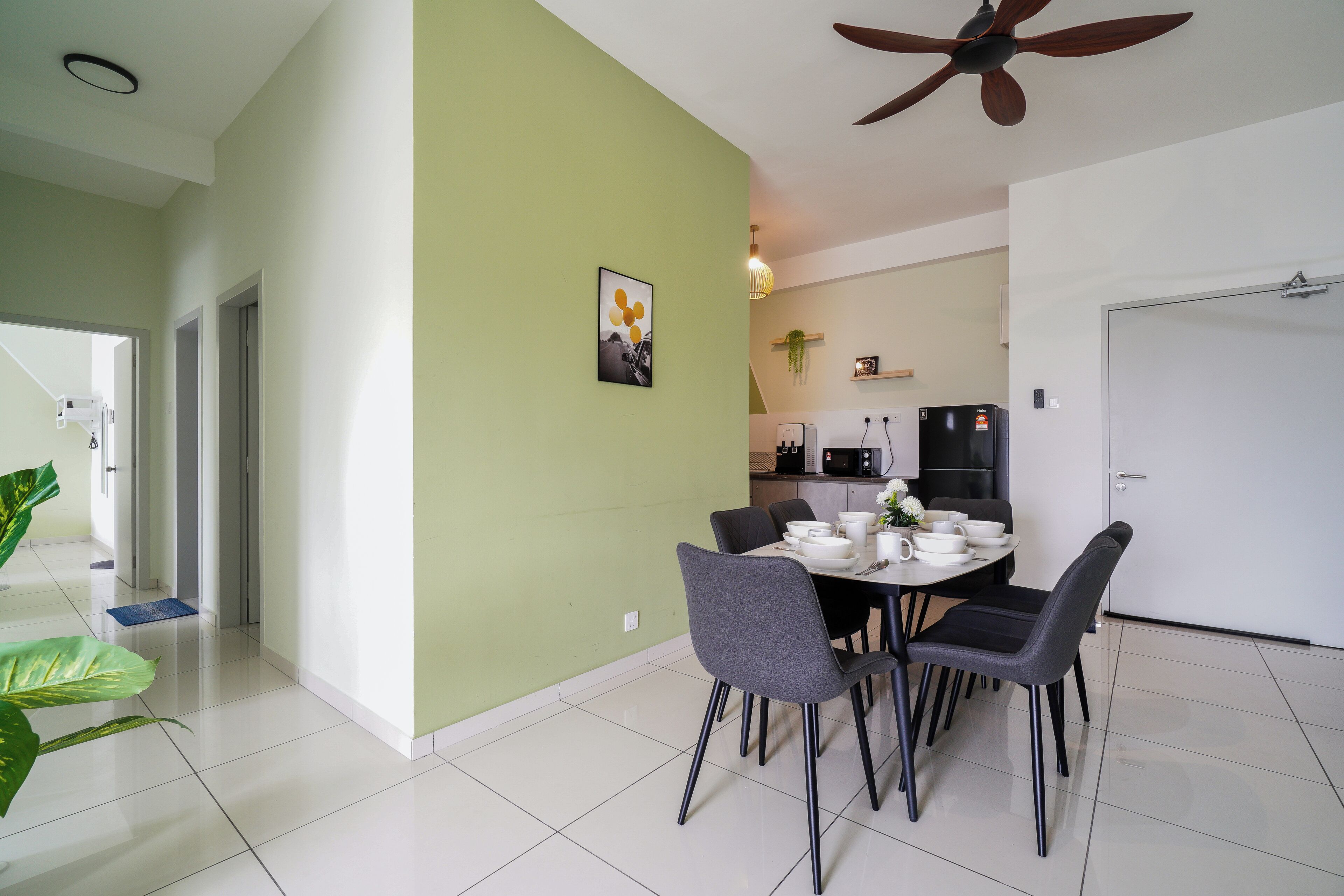 A dining area with a table set for four, a ceiling fan, and a green wall.