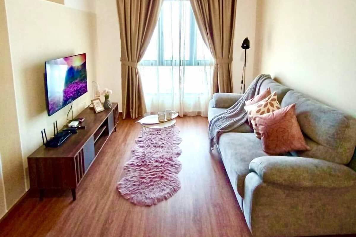 A living room with a ceiling fan, a flat-screen TV, a sofa, a coffee table, and a window with curtains.