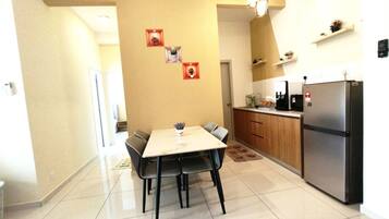 Una cocina moderna con comedor, que presenta un refrigerador de acero inoxidable, armarios de madera y piso de baldosas.