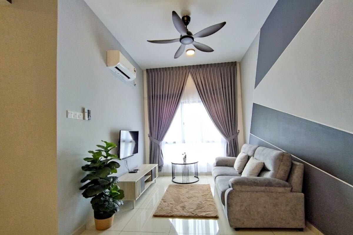 A modern living room with a sofa, a TV, a ceiling fan, and a potted plant.