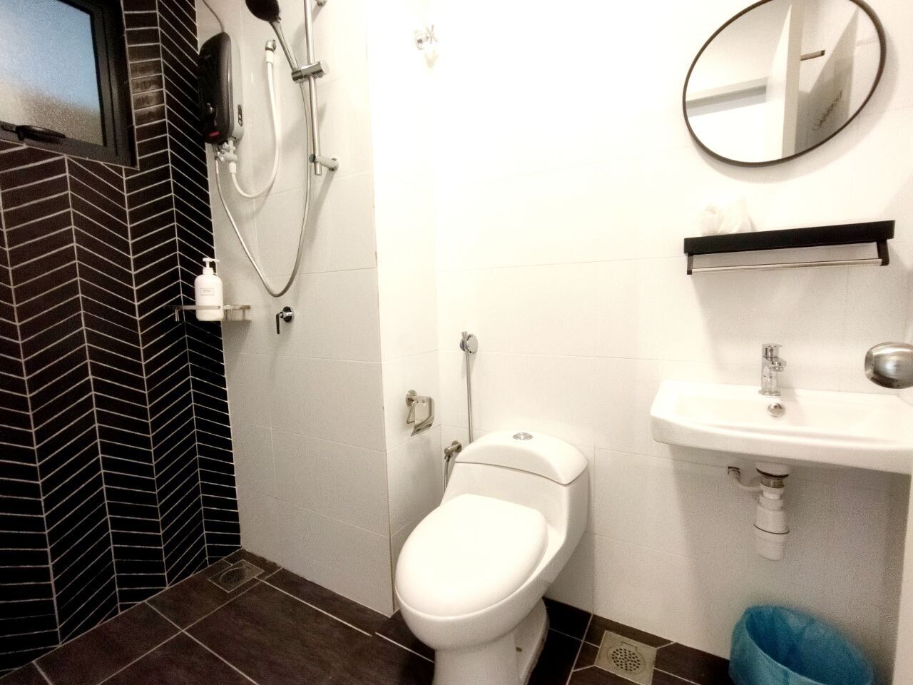A bathroom with a toilet, a sink, a mirror, and a shower.