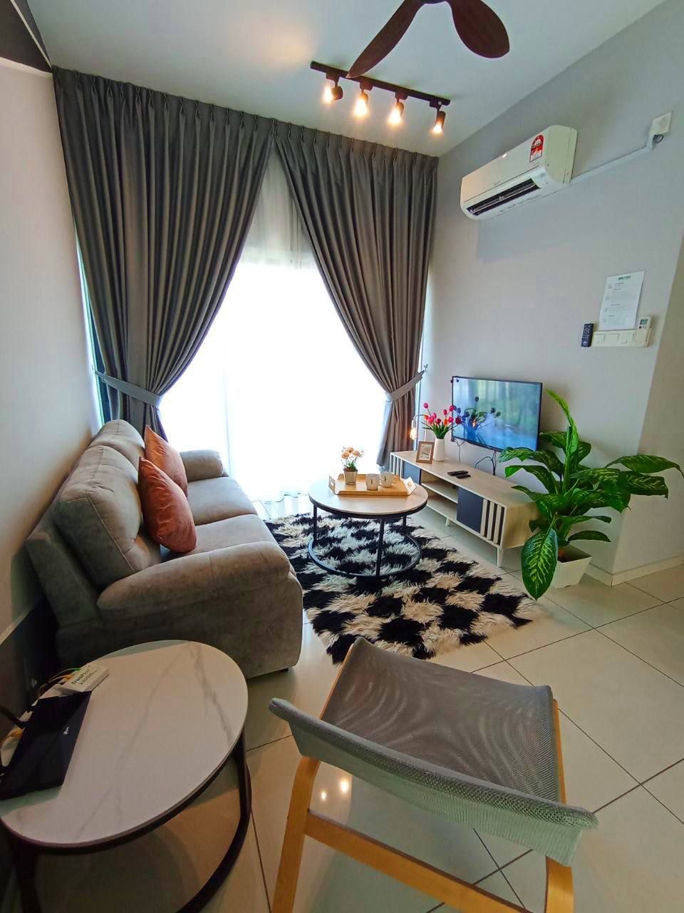 A modern living room with a sofa, a round coffee table, a TV, and a plant.