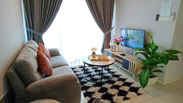 A modern living room with a sofa, a round coffee table, a TV, and a plant.