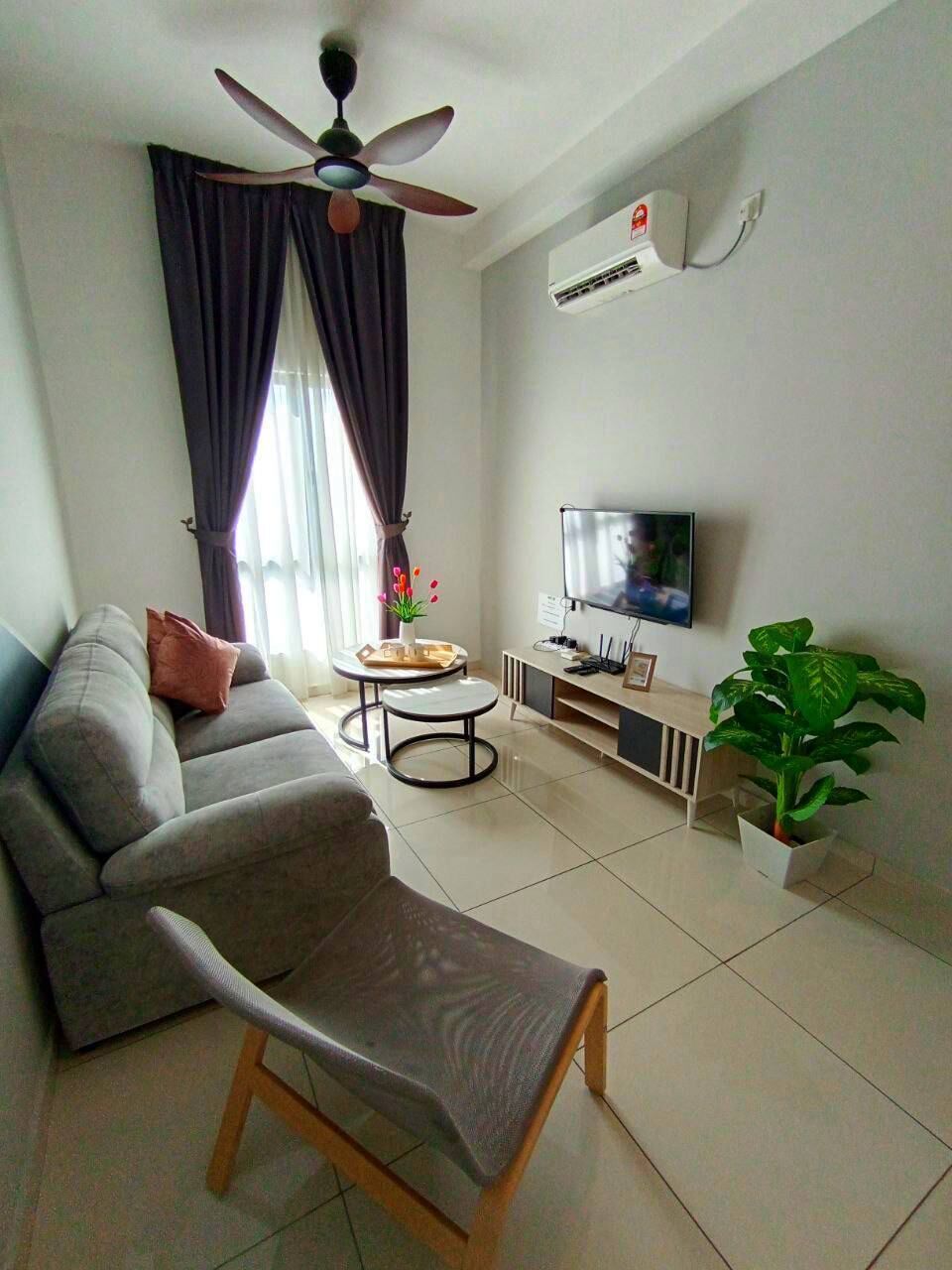 A living room with a sofa, a chair, a TV, a ceiling fan, and an air conditioning unit.