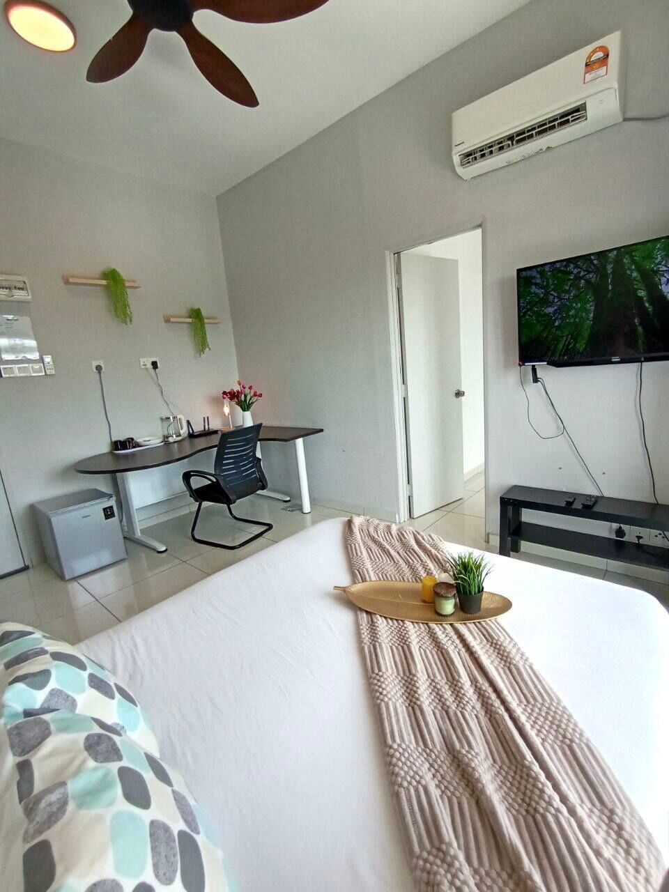 Une chambre d’hôtel équipée d’un lit, d’un bureau, d’une chaise, d’un climatiseur, d’une télévision et d’une fenêtre.