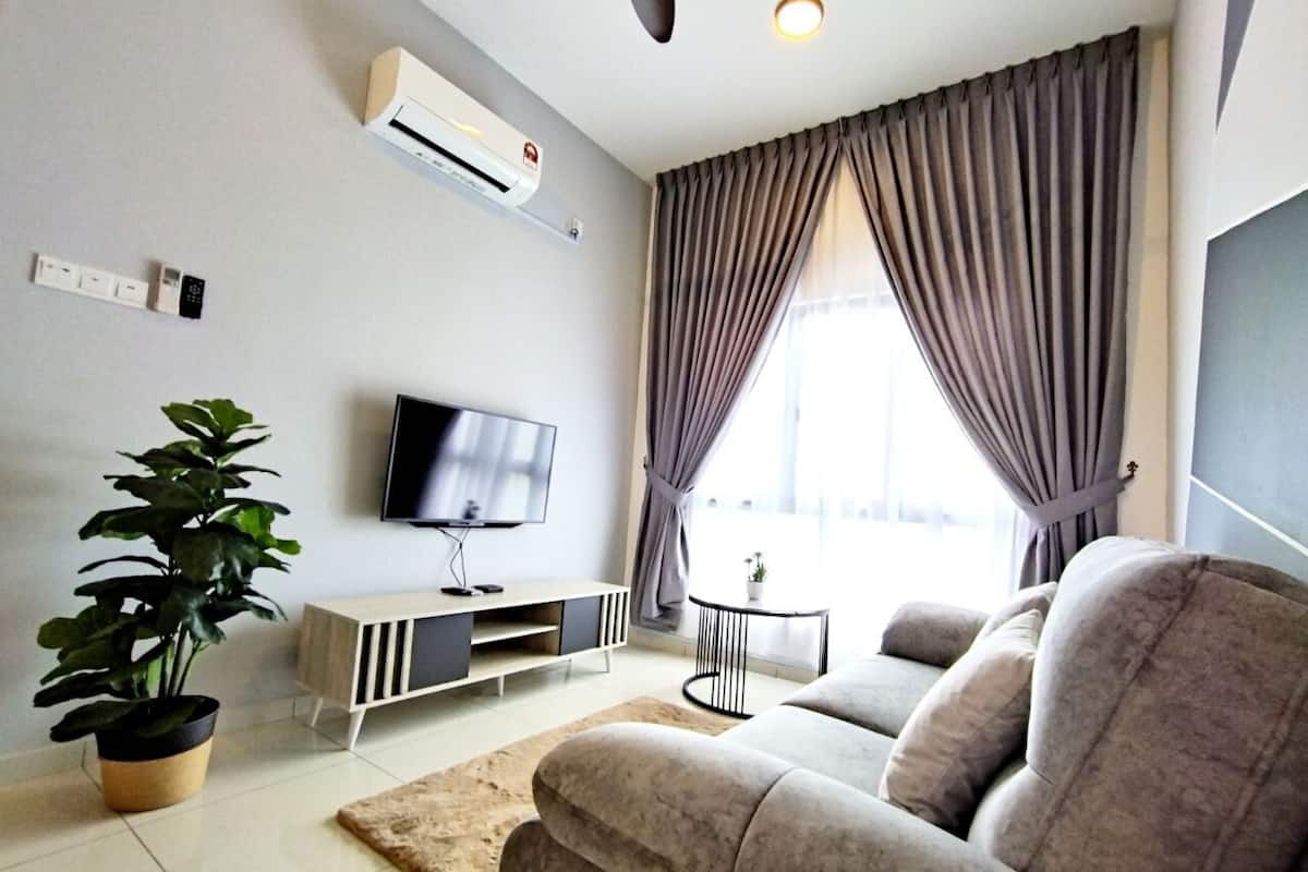 A modern living room with a sofa, a TV, a plant, and a small table.
